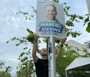 Der Kandidat hängt seine Wahlkampf Plakate an die Laterne